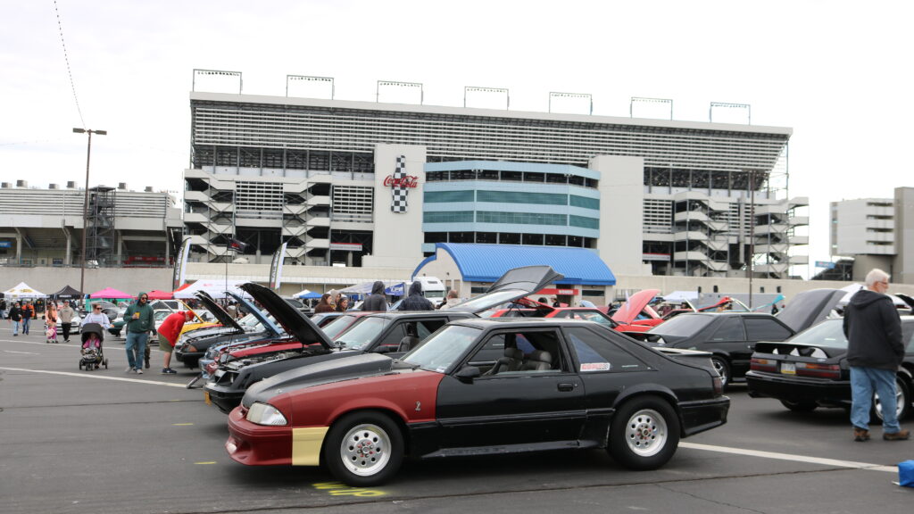 Ford Mustangs line in rows in front of Coca Cola sign at Charlotte Motor Speedway