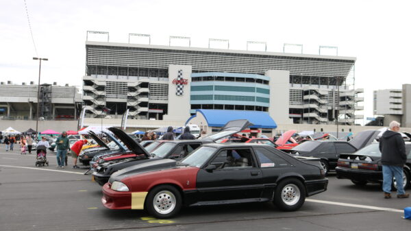 Ford Mustangs line in rows in front of Coca Cola sign at Charlotte Motor Speedway
