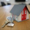 Stock photo of a small house and key on a table, representing the rental or housing market.