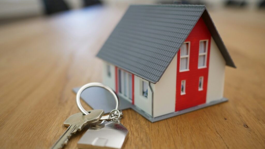 Stock photo of a small house and key on a table, representing the rental or housing market.