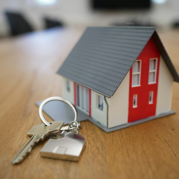 Stock photo of a small house and key on a table, representing the rental or housing market.