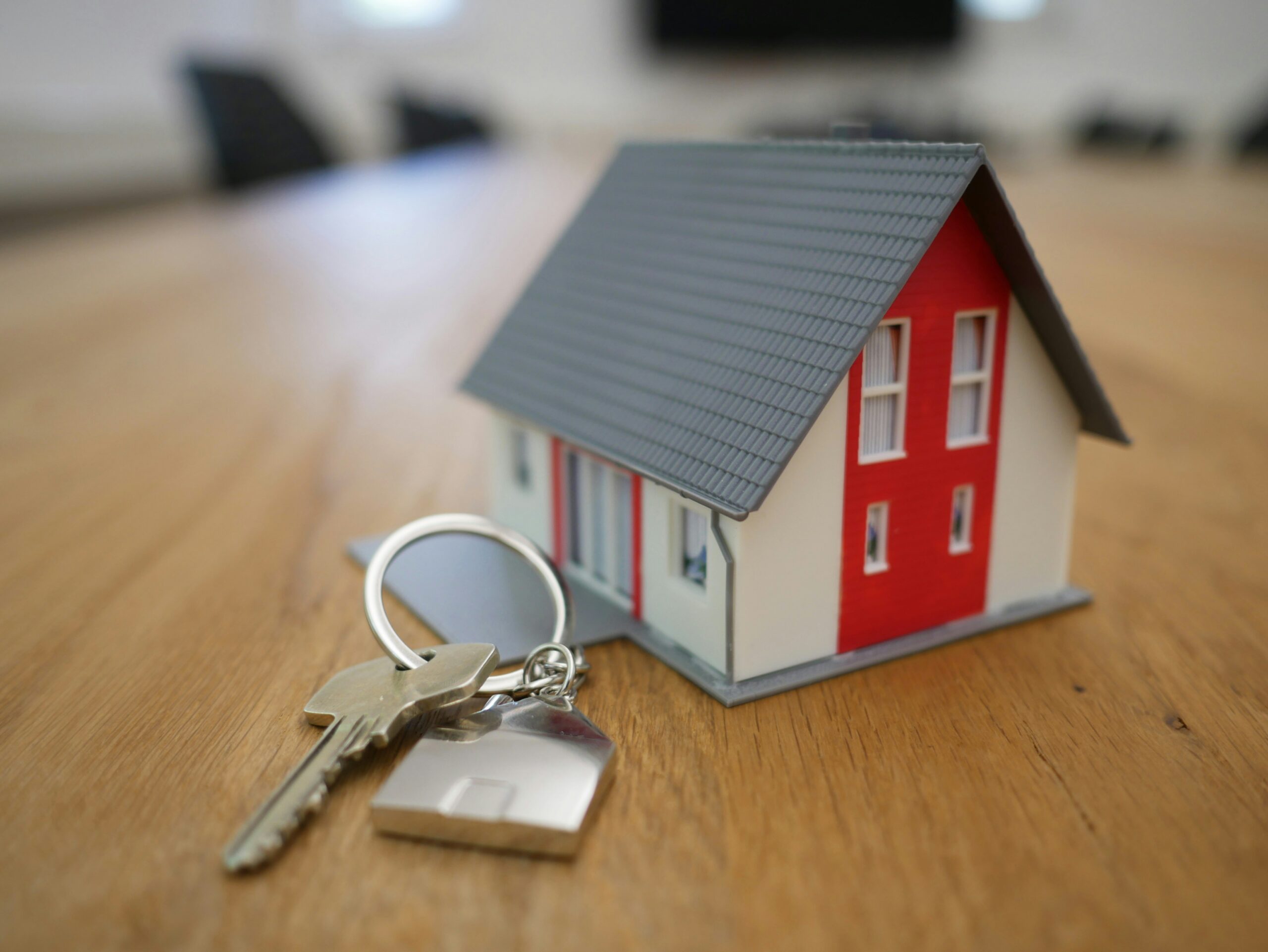 Stock photo of a small house and key on a table, representing the rental or housing market.